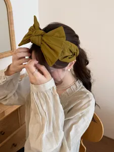 Vue détaillée d'un serre-tête à grand nœud jaune moutarde porté par un mannequin