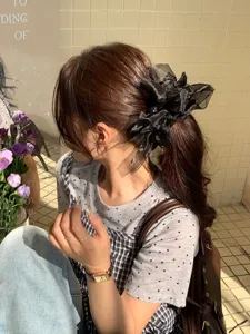 Chouchou élégant en maille noire avec nœud et strass porté sur une queue de cheval