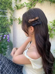 Elegant model wearing brown and black bow hair side combs in a soft outdoor setting