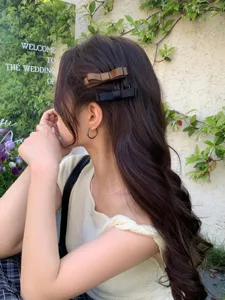 Close-up of elegant bow-knot hair clips worn by a model in a natural garden setting