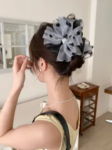 Rear view of a large polka dot mesh bow hair claw clip with elegant pearl center on dark hair.