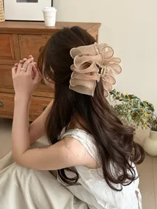 Gros plan d'une pince à cheveux nuage en maille plissée beige coiffée en chignon chic.