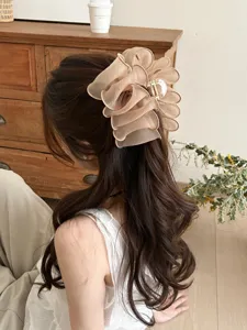 Élégante pince à cheveux fleur en maille plissée champagne sur longs cheveux bruns ondulés
