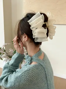 Détail macro élégant d'une pince à cheveux en tulle plissé sur un chignon de femme