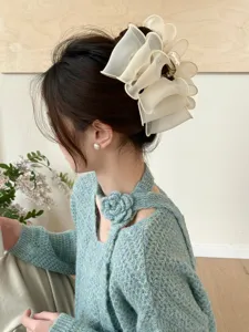 Pince à cheveux élégante en organza plissé crème portée sur un chignon stylisé