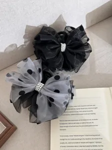 Elegant polka dot mesh bow hair claw clips with pearl detail on a fabric background