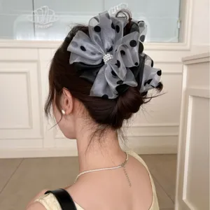 Elegant mesh polka dot bow hair claw clip with pearl accents shown on a brunette bun.