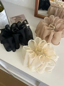 Vue détaillée des grandes pinces à cheveux en résille en coloris noir, beige et crème.