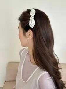 Detail shot showing a sweet white polka dot bow hair comb clip on long wavy brown hair