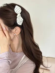 Detailed close-up showing a sweet polka dot bow hair comb worn on elegant brown wavy hair