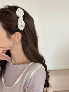 Close-up of a white polka dot bow hair comb styled on a brunette woman's hair