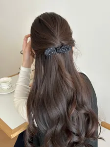 Detailed view of a sweet black polka dot bow hair comb styled in a half-up princess hair look