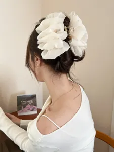 Detailaufnahme einer großen weißen Stoff-Haarklammer, die in einer eleganten Frisur sitzt