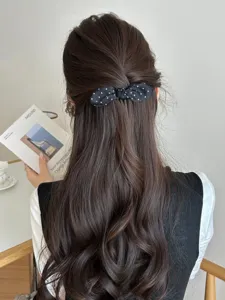 Back view of a polka dot bow hair comb styling a half-up princess hair