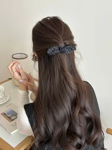 Elegant black polka dot bow hair comb styled in a sweet half-up ponytail back view