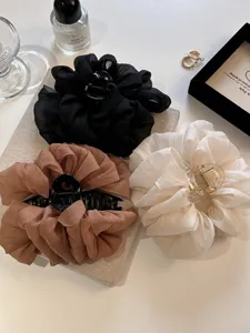 Drei übergroße Chiffon-Haarklammern in den Farben Schwarz, Weiß und Braun.