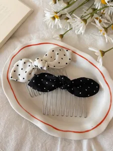 Detail shot of black and white polka dot bow hair combs on a decorative plate