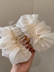 Detaillierte Ansicht von flauschigen weißen Haarklammern aus Chiffon-Rüschen in der Hand