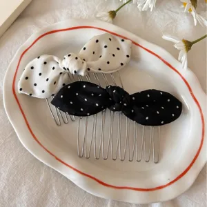 Polka dot bow hair combs in black and white colors on a white ceramic plate.