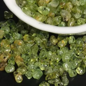 Detail view of irregular green crystal chips with drilled holes for DIY jewelry crafting.