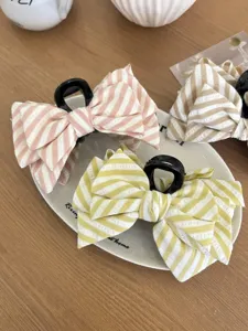 Dettaglio di tre mollette per capelli a righe con fiocco in rosa, giallo e beige