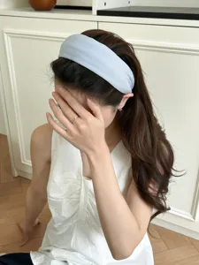 Detail view of light blue ribbed knit wide headband on model with high crown effect