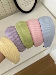 Detail showing a variety of cream-colored ribbed knit headbands in pastel shades