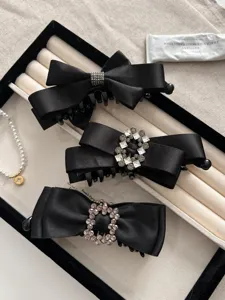 Detail of three black satin bow hair clips with exquisite rhinestone buckles