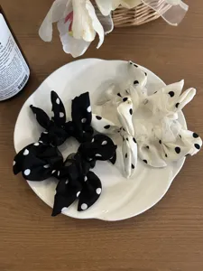 Detailed close-up of polka dot bow scrunchies in black and white on a white plate