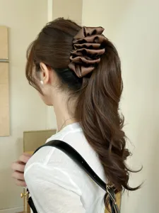 Detailed rear view of an elegant large brown ruffled banana hair clip on a ponytail