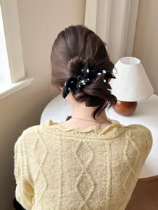 Detailed shot of a black and white polka dot bow scrunchie on a stylish low bun hairstyle.