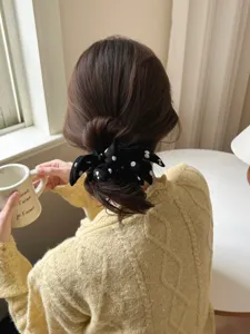 Detailed view of a stylish black polka dot bow scrunchie on a soft low bun hairstyle.