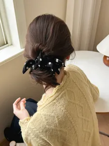 Back view detail of a black and white polka dot bow scrunchie on a stylish hair bun