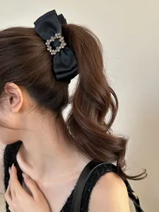 Detailed view of an elegant black bow hair clip with rhinestone square buckle on hair