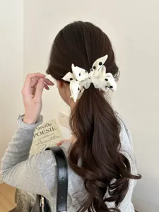 Detail view of a white polka dot bow scrunchie styled on a brunette ponytail.