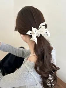 Rear view detail showing a white polka dot bow hair scrunchie on a brunette ponytail