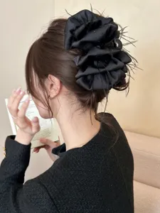 Detail view showing a large black bubble flower hair claw clip with delicate feathers in hair