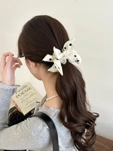 Close-up of a white polka dot bow scrunchie styling a brown ponytail