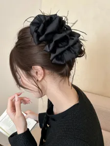 Detailed view of an elegant black fabric hair claw clip with delicate feathers