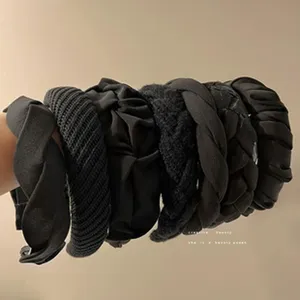 Close-up of various textured black headbands for a trendy high-volume hair look.