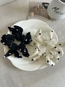 Detailed close-up of black and white polka dot bow scrunchies on a ceramic plate