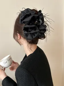 Detailed view of an elegant black bow hair claw clip with feathers and rhinestones on hair