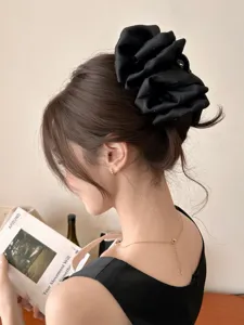 Detailed view of an elegant large black fabric bow hair claw clip worn in an updo hairstyle