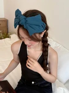 Mannequin asiatique élégant portant un large bandeau nœud 3D bleu marine dans une chambre