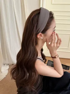 Vista detallada de una diadema ancha gris minimalista sobre cabello ondulado