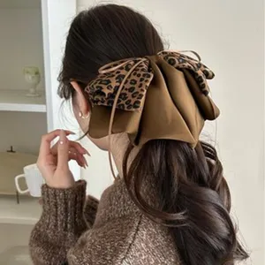 Détail d'une pince à cheveux avec nœud en satin marron et motif léopard sur modèle