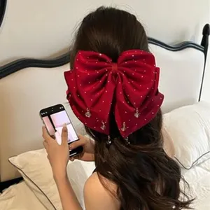 Détail d'une grande pince à cheveux en satin rouge ornée de strass et de petits charms.
