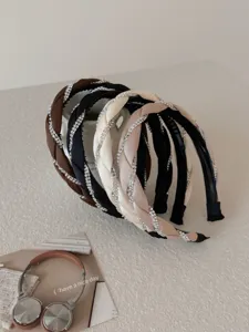 Close-up view of elegant braided headbands stacked with sparkling rhinestone details