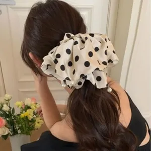 Detailed view of an oversized polka-dot scrunchie with pearls on a low ponytail hair style