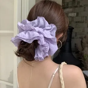 Close-up detail of an oversized purple ruffled scrunchie accessory worn on a low ponytail